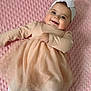 Arzugul is registered to the contest to win money with this photo: baby, girl, smiling, dress, headband, bow, blanket, pink, white_tights, infant, cute, lying_down, soft_texture, embroidered_text, happy, indoors, child, portrait, baby_clothes, headwear