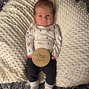 Noah is registered to the contest to win money with this photo: baby, infant, newborn, one_month, cushion, blanket, clothing, onesie, socks, wooden_sign, cute, portrait, lying_down, patterned_blanket, comfortable, indoor, face, expression, small_hands, soft_texture