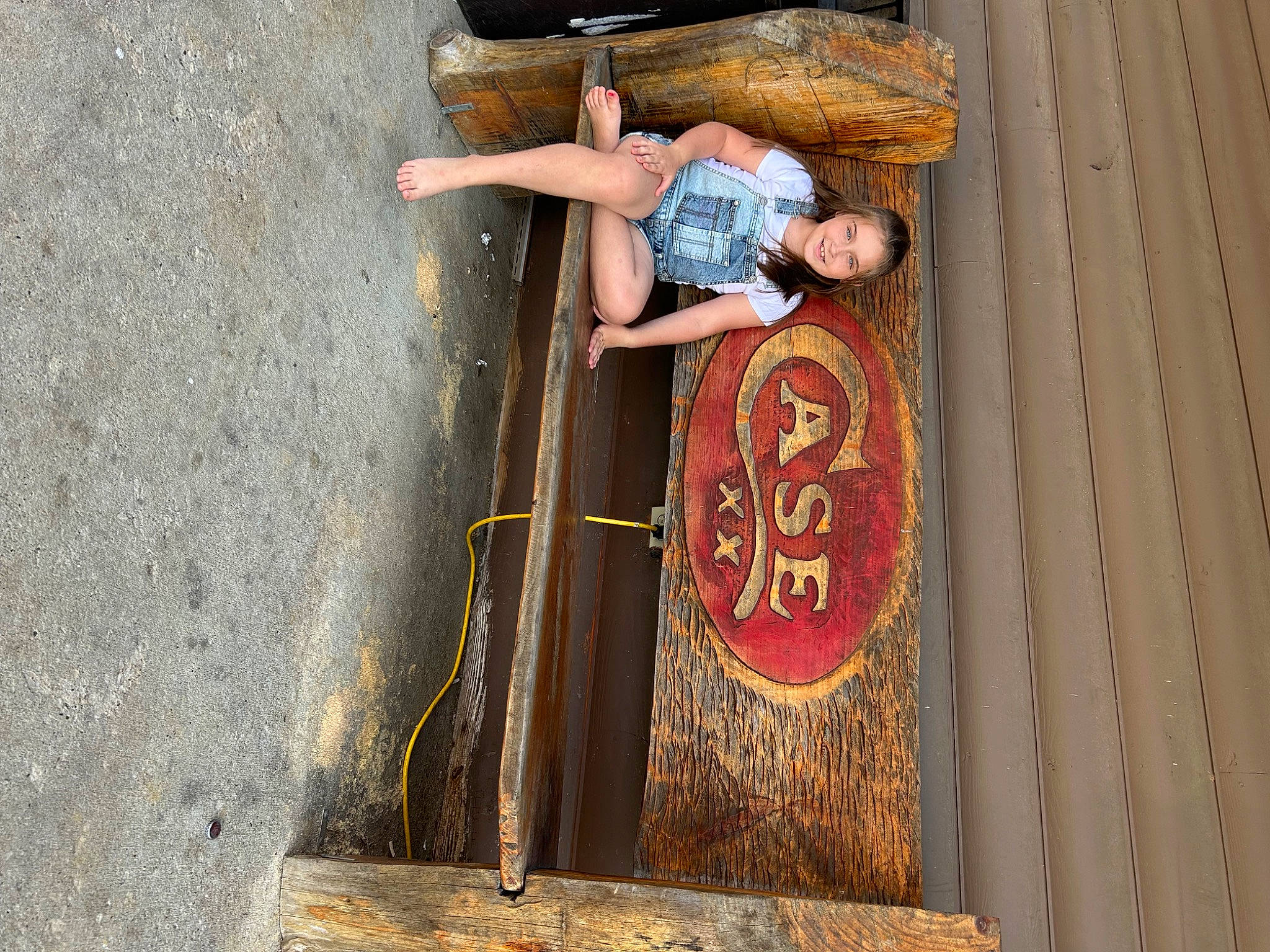 Zoey is registered to the contest to win money with this photo: concrete, hat, joy, landscape, leisure, logo, metal, person, road_surface, rolling, sitting, t_shirt, toddler, travel, visual_arts, wall, wood, wood_stain