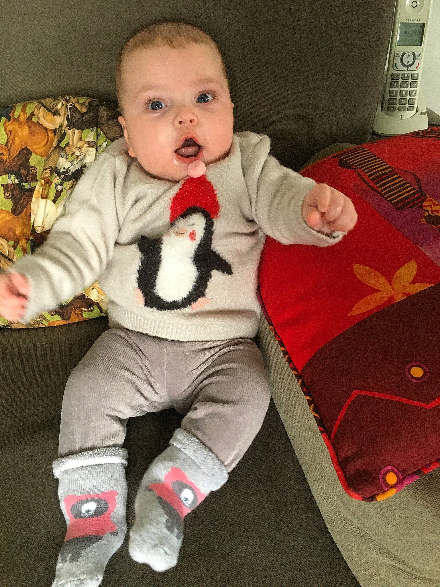 Enola a rejoint le concours — aidez-le/la à gagner de superbes lots ! baby, baby_toddler_clothing, cheek, child, comfort, eye, finger, head, human_body, linens, mammal, outerwear, person, sitting, sleeve, sock, surprise, t_shirt, telephone, textile