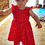 child, curly_hair, cute, daylight, expression, flooring, footwear, home, indoor, person, playmat, red_dress, sandal, standing, tiles, toddler, toy, walking, white_hat, young_child
