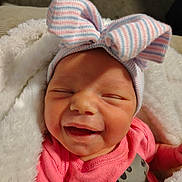 Alyvia joined the competition — help win amazing prizes! baby, newborn, smiling, pink_clothing, striped_hat, bow, blanket, cozy, infant, cute, happy, face, sleepy, small_hand, soft_texture, warm, child, portrait, indoors, closeup