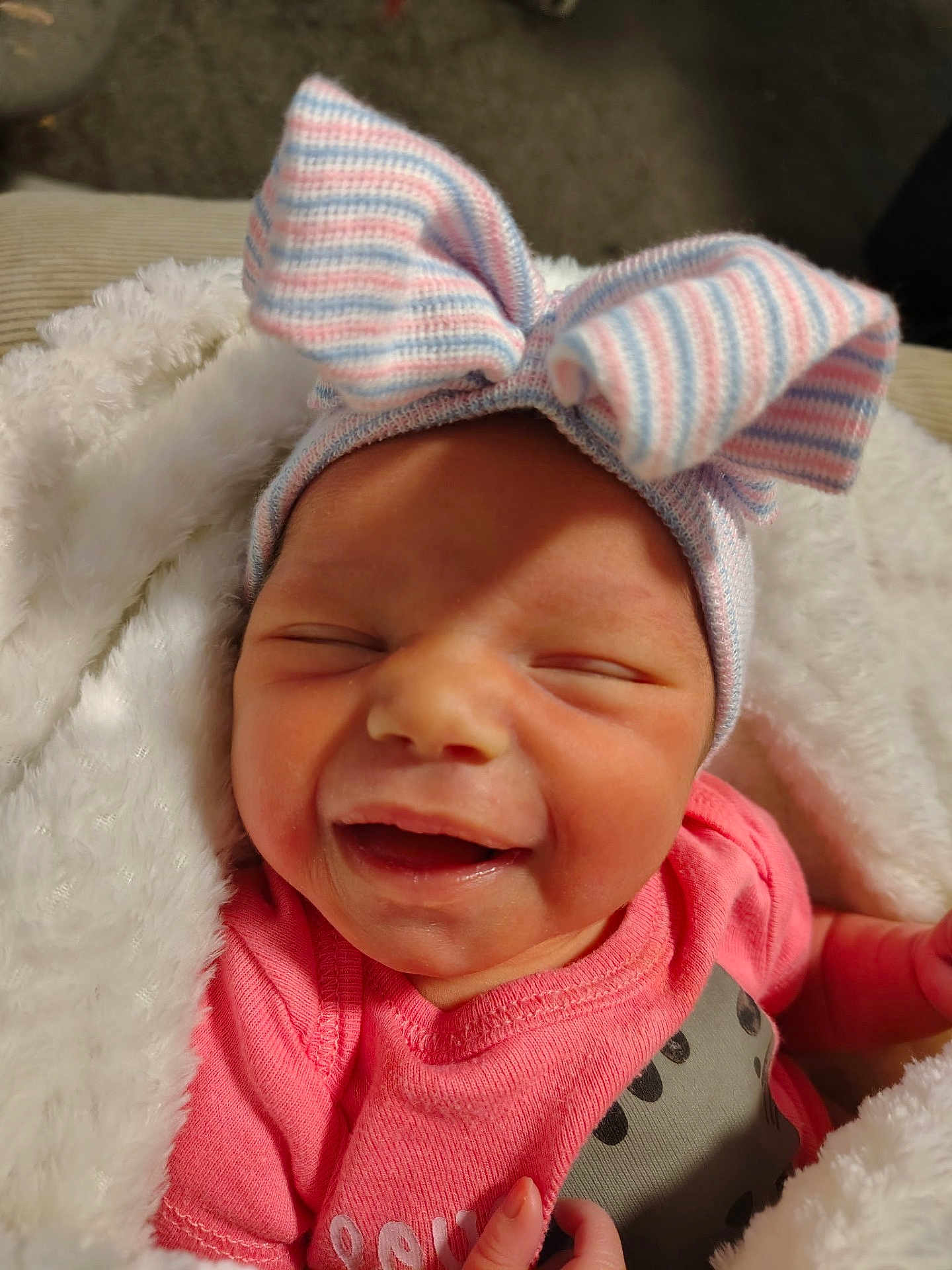 Alyvia joined the competition — help win amazing prizes! baby, newborn, smiling, pink_clothing, striped_hat, bow, blanket, cozy, infant, cute, happy, face, sleepy, small_hand, soft_texture, warm, child, portrait, indoors, closeup