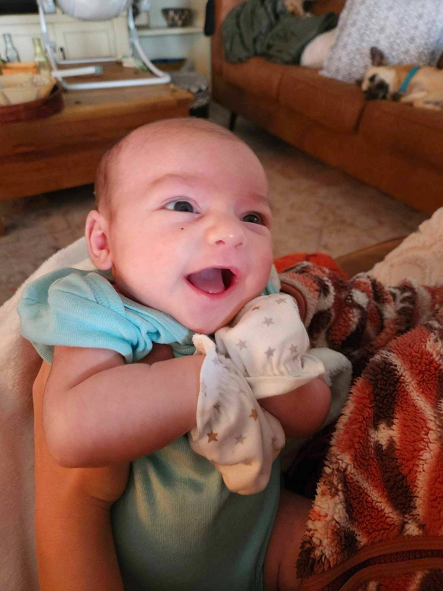 Nathan is registered to the contest to win money with this photo: baby, baby_toddler_clothing, cheek, child, comfort, couch, eye, finger, happy, head, iris, linens, mouth, nail, person, room, sitting, skin, smile, toddler