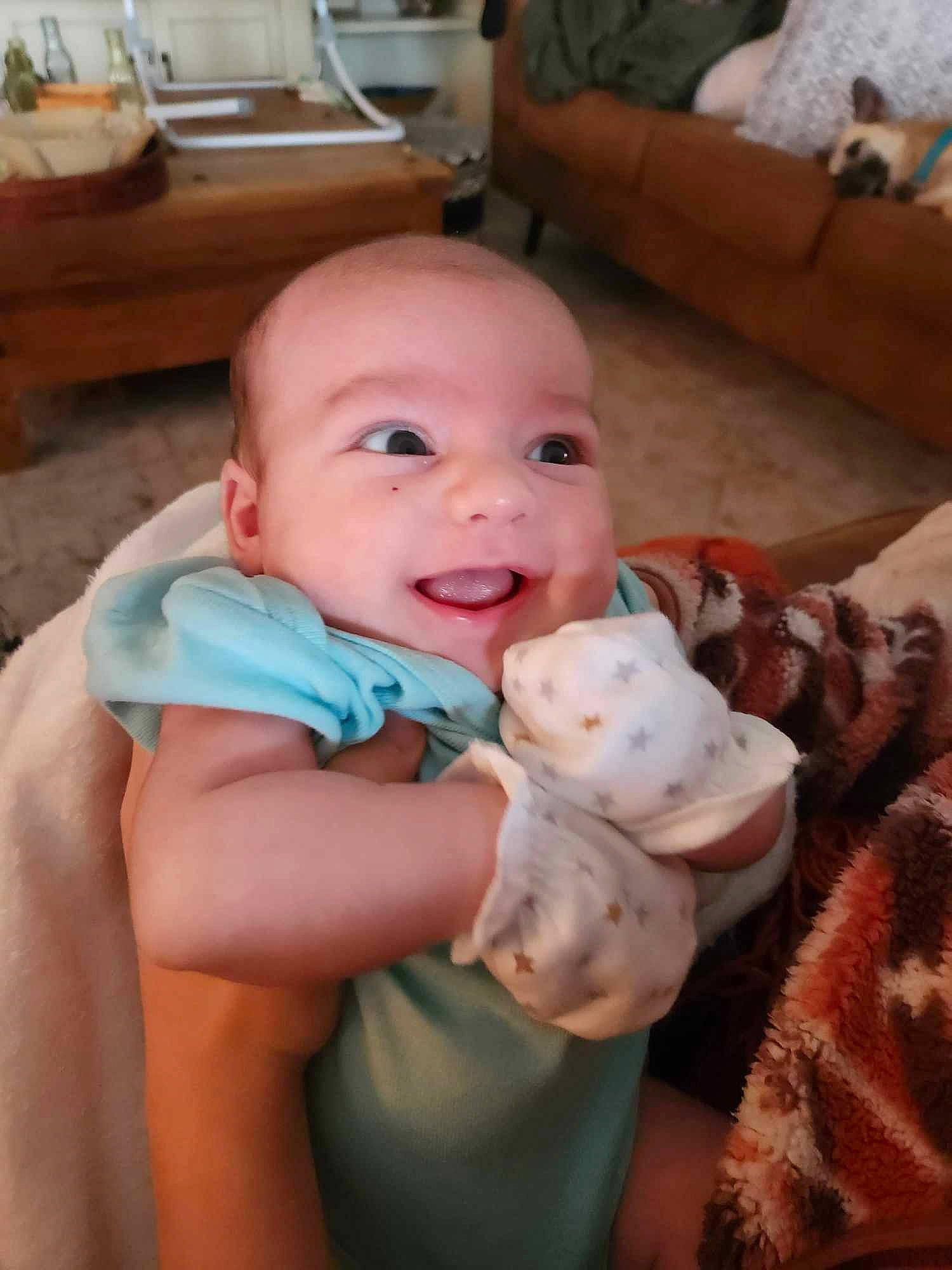 Nathan is registered to the contest to win money with this photo: baby, baby_toddler_clothing, cheek, child, comfort, couch, finger, flooring, happy, hardwood, kitchen_appliance, linens, nail, person, room, sitting, skin, smile, thumb, toddler