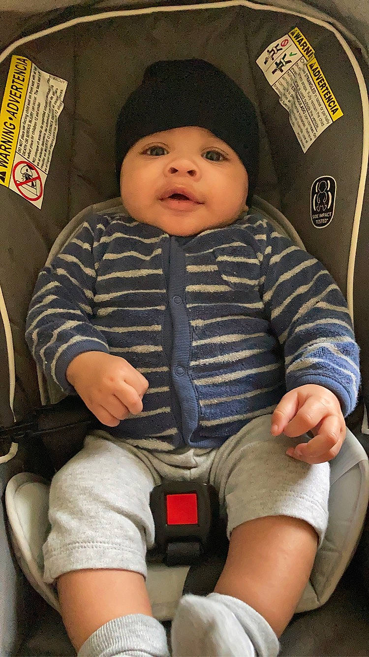 Demarieo is registered to the contest to win money with this photo: baby, baby_toddler_clothing, car_seat, cheek, child, clothing, comfort, cool, facial_expression, headwear, human_leg, knee, lap, people, person, shorts, sitting, skin, sleeve, smile