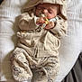 baby, infant, sleeping, pacifier, hoodie, beige_clothing, cute, cushion, blanket, toy, white_socks, patterned_pants, child, resting, indoors, soft_lighting, comfort, peaceful, newborn, portrait