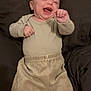 baby, infant, laughing, clothing, neutral_colors, cushion, cozy, indoor, person, cute, happy, child, smiling, sitting, long_sleeve, pants, white_socks, head, skin, small_hands