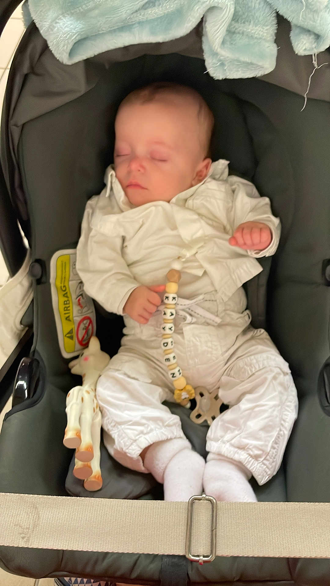 Kayden participe au concours pour gagner de l'argent avec cette photo : baby, sleeping, stroller, white_clothing, pacifier_clip, toy, giraffe, blanket, infant, child, peaceful, cute, indoors, soft_lighting, comfort, resting, baby_accessory, toddler, person, car_seat