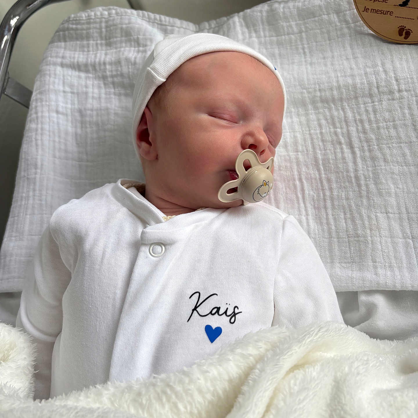 Kaïs a rejoint le concours — aidez-le/la à gagner de superbes lots ! newborn, baby, sleeping, pacifier, white_clothing, hat, blanket, hospital_bassinet, face, infant, soft_texture, peaceful, indoors, child, portrait, cute, resting, cozy, newborn_baby, baby_boy