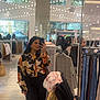woman, mirror, selfie, clothing_store, stroller, child, blanket, shopping, clothes, pants, blouse, reflection, lights, people, shopping_bags, coat, jeans, rack, indoor, retail