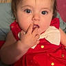 Arianna is registered to the contest to win money with this photo: baby, child, red_dress, gold_polka_dots, white_bow, fingers_in_mouth, blue_eyes, curly_hair, cute, portrait, indoors, soft_background, infant, expression, closeup, sitting, adorable, young_child, skin, face