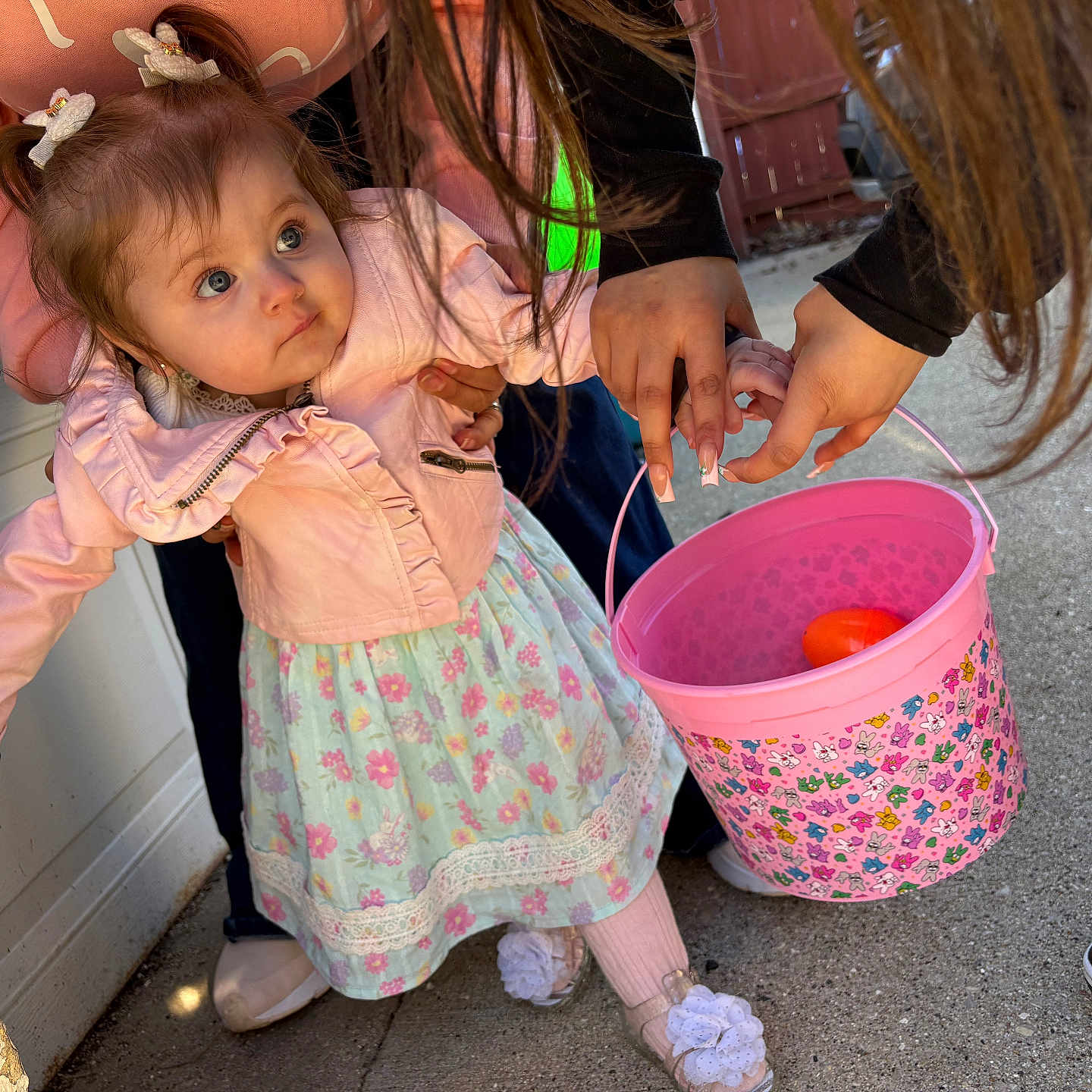 Arianna joined the competition — help win amazing prizes! toddler, child, pink_jacket, floral_dress, bucket, outdoor, concrete, pony_tails, hands, sneakers, curious, sunlight, play, support, person, flowers, clothing, footwear, wall, concrete_floor