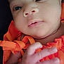 baby, close_up, face, hand, orange_clothing, infant, cute, skin, portrait, newborn, child, person, expression, young, soft_light, indoors, human, small_hand, clothing, baby_face
