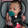 baby, infant, pacifier, car_seat, seatbelt, child, pink_clothing, butterfly_design, curly_hair, close_up, indoors, seat, straps, sitting, young_child, cute, secure, hand, face, portrait