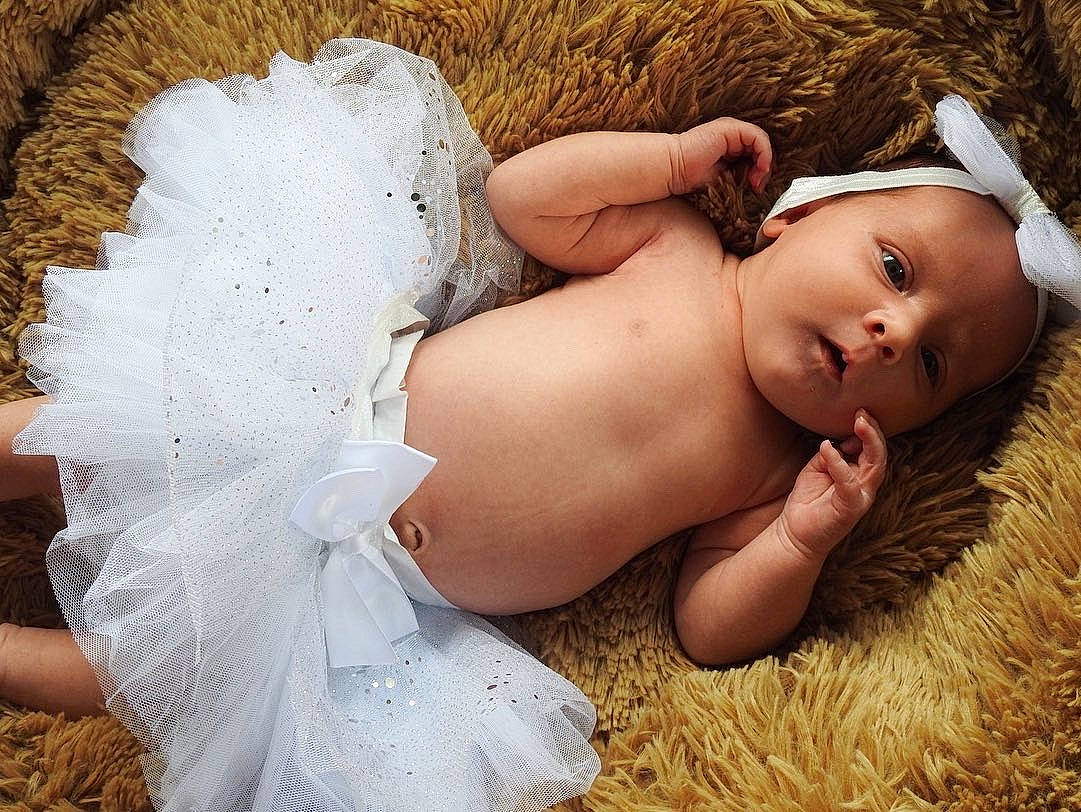 Tahlia is registered to the contest to win money with this photo: abdomen, baby, chest, fashion_accessory, fawn, flash_photography, grass, happy, headpiece, human_body, human_leg, leg, people_in_nature, person, sitting, skin, thigh, toddler, trunk, wedding_dress