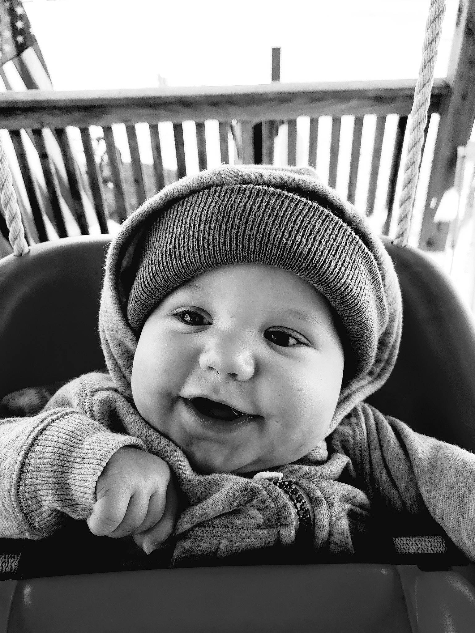 Benton is registered to the contest to win money with this photo: baby, black, black_and_white, cap, cheek, child, comfort, cool, face, flash_photography, happy, headwear, monochrome, monochrome_photography, mouth, outerwear, person, sitting, smile, style