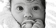 Mia joined the competition — help win amazing prizes! baby, infant, pacifier, towel, close_up, black_and_white, face, hand, curly_hair, expression, portrait, cute, child, newborn, sleepy, soft_texture, wrapped, indoors, skin, eyes