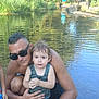 Andrés a rejoint le concours — aidez-le/la à gagner de superbes lots ! child, adult, water, river, trees, outdoor, nature, people, summer, swimwear, sunglasses, rocks, reflection, sunlight, tank_top, shorts, sandals, family, recreation, daytime