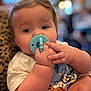 baby, blue, blurred_background, child, close_up, cute, face, hand, holding, indoor, infant, leopard_print, pacifier, pattern, person, portrait, shirt, skin, soft_lighting, toddler