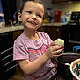 bowl, cabinet, celebration, child, cute, decorative, earrings, easter_egg, food, glass_table, happy, holiday, indoor, kitchen, person, pink_shirt, portrait, smiling, table, wood_floor