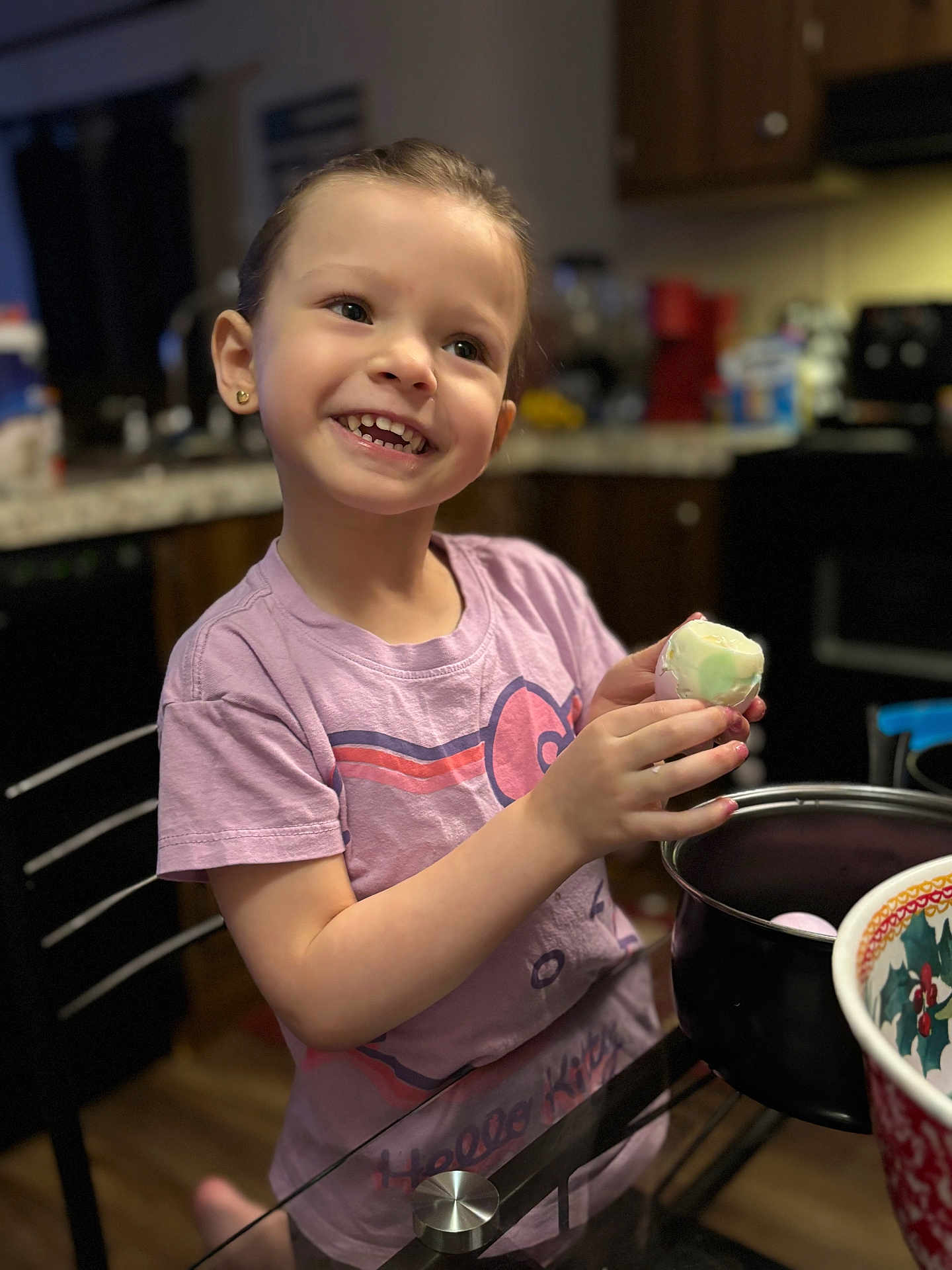 Anna is registered to the contest to win money with this photo: bowl, cabinet, celebration, child, cute, decorative, earrings, easter_egg, food, glass_table, happy, holiday, indoor, kitchen, person, pink_shirt, portrait, smiling, table, wood_floor