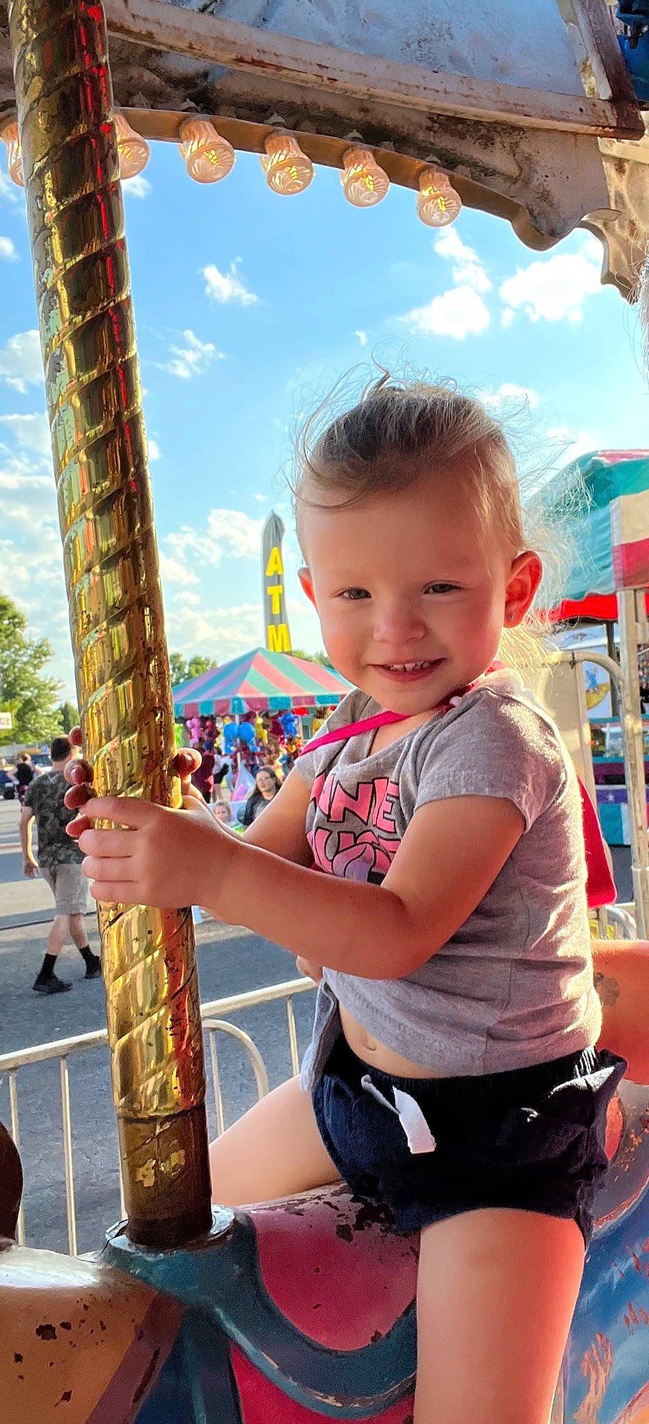 Anna is registered to the contest to win money with this photo: child, city, cloud, event, fun, happy, human_settlement, joy, leisure, nonbuilding_structure, person, photograph, pole, recreation, sky, smile, snapshot, summer, t_shirt, toddler