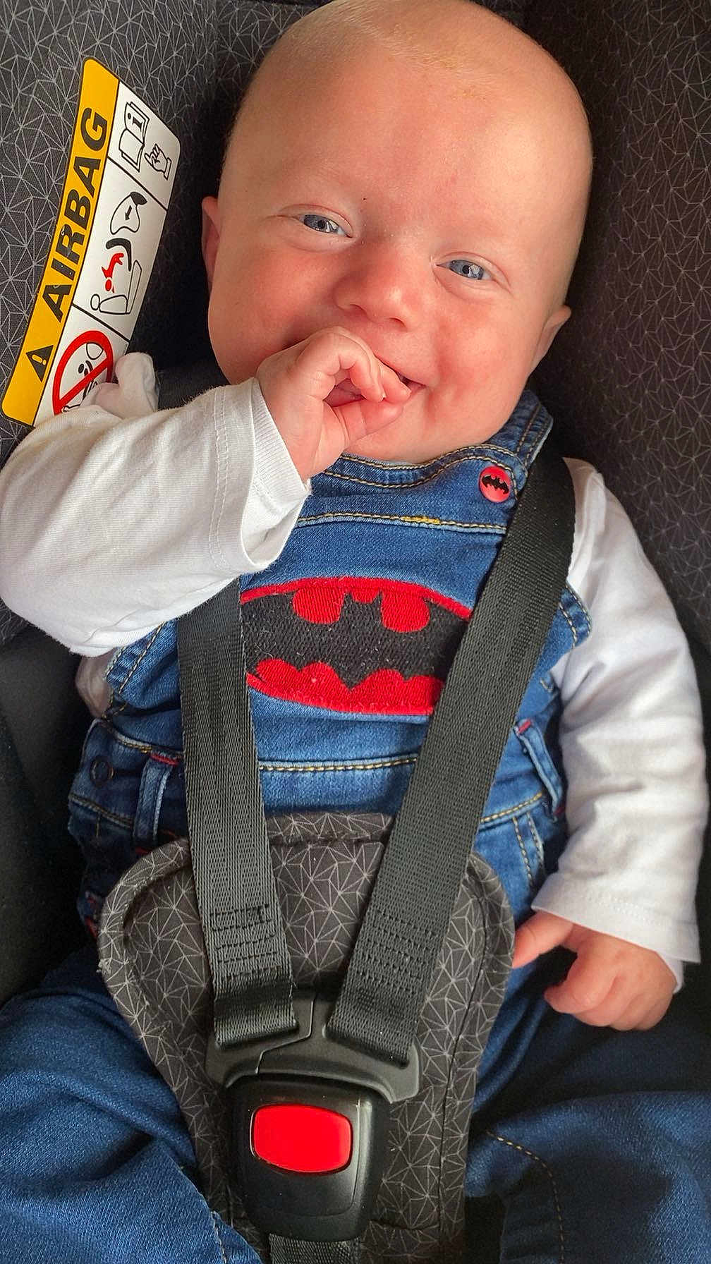 Nolan participe au concours pour gagner de l'argent avec cette photo : baby, child, car_seat, denim, batman_logo, smile, blue_eyes, infant, safety_harness, cute, happy, hand, clothing, seatbelt, portrait, indoor, person, small_child, face, young