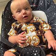 Nolan participe au concours pour gagner de l'argent avec cette photo : baby, infant, child, star_pattern, black_seat, patterned_shirt, blue_eyes, indoor, window, sitting, clothing, seatbelt, cute, person, furniture, floor, expression, hand, legs, portrait