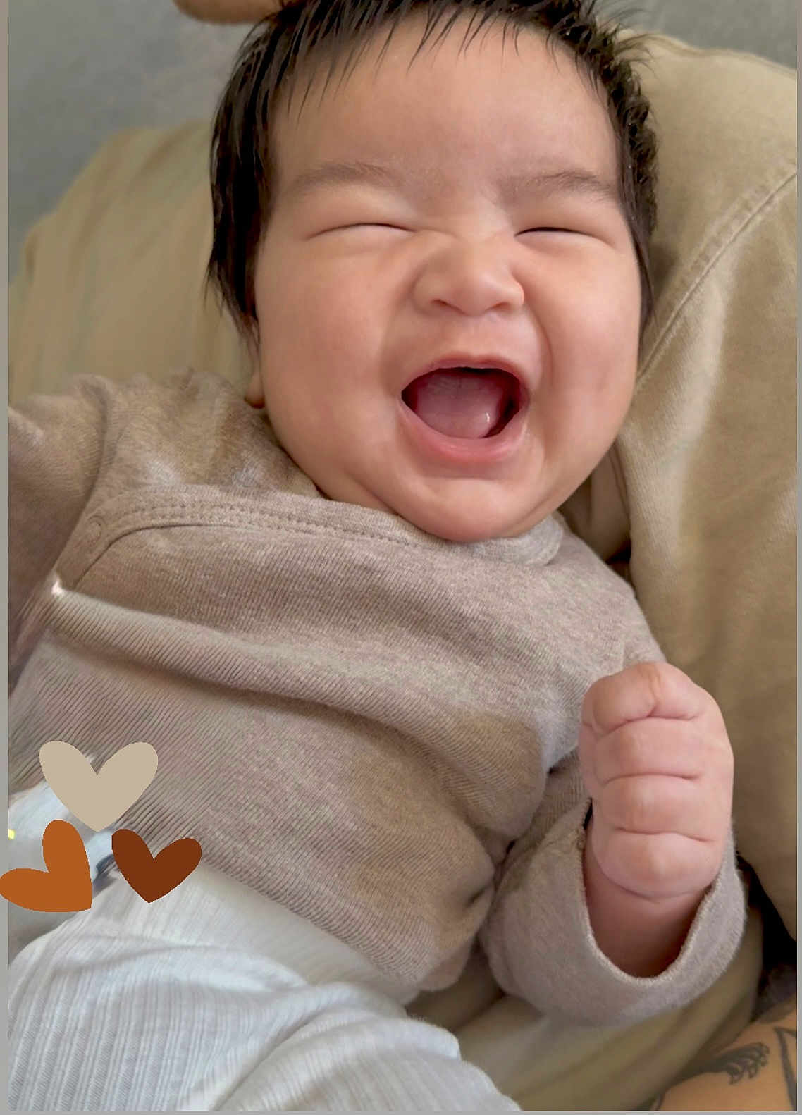 Kai is registered to the contest to win money with this photo: baby, smiling, laughing, infant, clothing, sweater, pants, hand, fist, happy, portrait, cute, joy, skin, face, hair, furniture, cozy, heart, lying_down