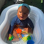 Sohan participe au concours pour gagner de l'argent avec cette photo : baby, bandana, blue_shirt, child, fun, grass, grill, happy, inflatable_pool, outdoor, patio, playful, shadow, sitting, smiling, summer, sunlight, toys, water, water_play