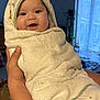 baby, infant, towel, wrapped, smiling, face, hand, indoors, window, curtains, plant, cozy, cute, child, person, blanket, soft, hooded_towel, home, happy