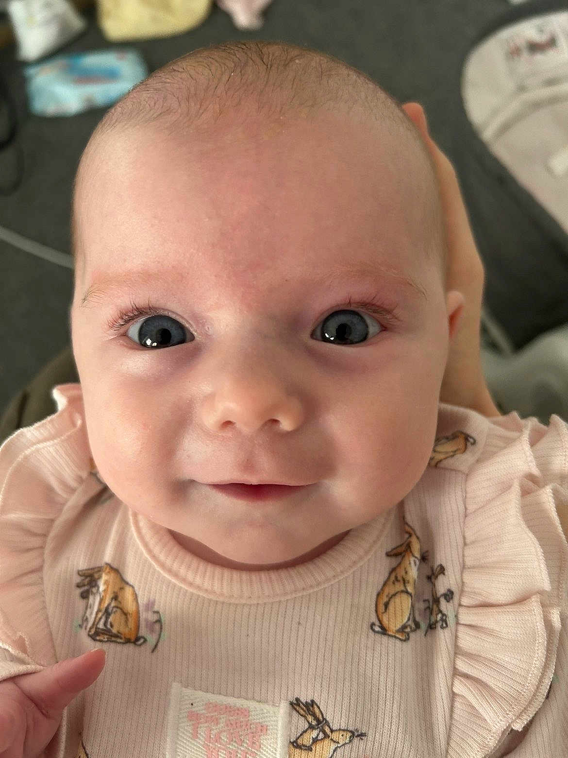 Luna is registered to the contest to win money with this photo: baby, infant, face, eyes, smile, pink_clothing, animal_print, cute, close_up, person, human, child, newborn, soft_lighting, hand, portrait, adorable, young, baby_girl, expression