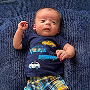 Elias joined the competition — help win amazing prizes! baby, infant, child, blue_shirt, cars, plaid_shorts, blanket, texture, cute, laying_down, hand, face, eyes, clothing, pattern, colorful, young, portrait, indoors, casual