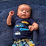 baby, infant, child, blue_shirt, cars, plaid_shorts, blanket, texture, cute, laying_down, hand, face, eyes, clothing, pattern, colorful, young, portrait, indoors, casual