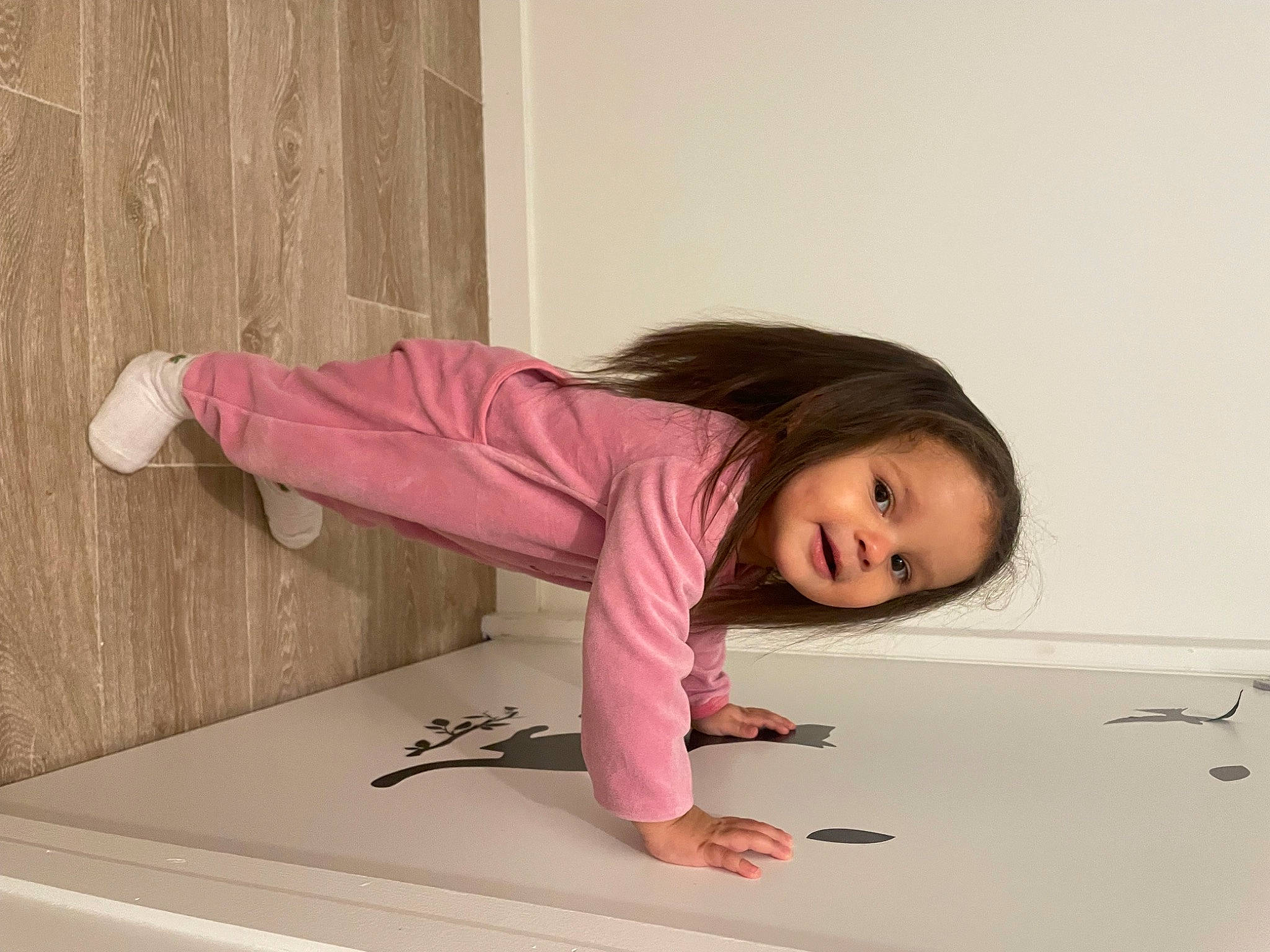 Lila a rejoint le concours — aidez-le/la à gagner de superbes lots ! baby_toddler_clothing, child, comfort, floor, flooring, happy, hardwood, jacket, knee, kneeling, magenta, outerwear, person, pink, room, skin, sleeve, smile, sock, toddler