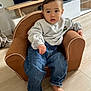 armchair, barefoot, casual_wear, child, clothing, curious, cute, expression, floor, furniture, home, indoor, jeans, living_room, person, relaxed, seated, sweatshirt, toddler, young_child