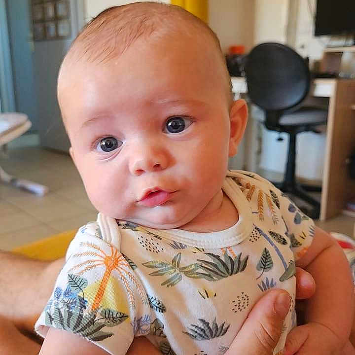 Lowan a rejoint le concours — aidez-le/la à gagner de superbes lots ! baby, chair, child, curious, curtain, expression, face, furniture, hand, home, indoor, infant, onesie, patterned_clothing, person, portrait, room, seated, skin, young