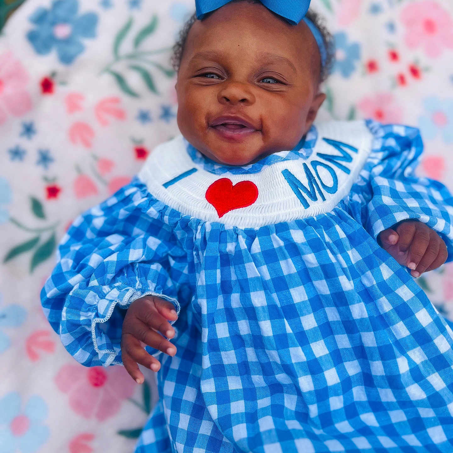 Sanye joined the competition — help win amazing prizes! baby, baby_girl, blue_bow, blue_dress, checkered_pattern, child, closeup, clothing, colorful, cute, floral_blanket, happy, headband, infant, lying_down, person, portrait, skin, smile, soft_texture