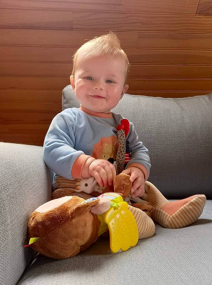 Eliott participe au concours pour gagner de l'argent avec cette photo : baby, baby_playing_with_toys, baby_toddler_clothing, child, comfort, couch, foot, happy, head, human_leg, joy, knee, lap, person, sitting, sleeve, smile, stuffed_toy, thumb, toddler