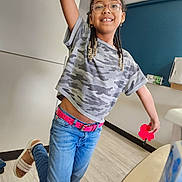 Jolie joined the competition — help win amazing prizes! child, girl, smiling, glasses, braids, jeans, camouflage_shirt, pink_belt, pop_it_toy, indoor, wooden_floor, happy, playful, casual_clothing, footwear, earrings, young_person, portrait, dancing, fun