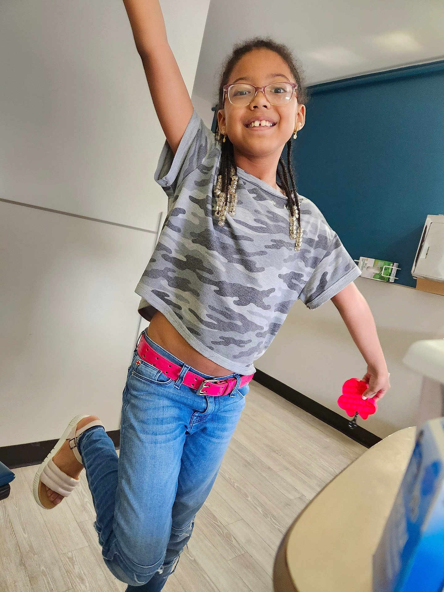 Jolie joined the competition — help win amazing prizes! child, girl, smiling, glasses, braids, jeans, camouflage_shirt, pink_belt, pop_it_toy, indoor, wooden_floor, happy, playful, casual_clothing, footwear, earrings, young_person, portrait, dancing, fun