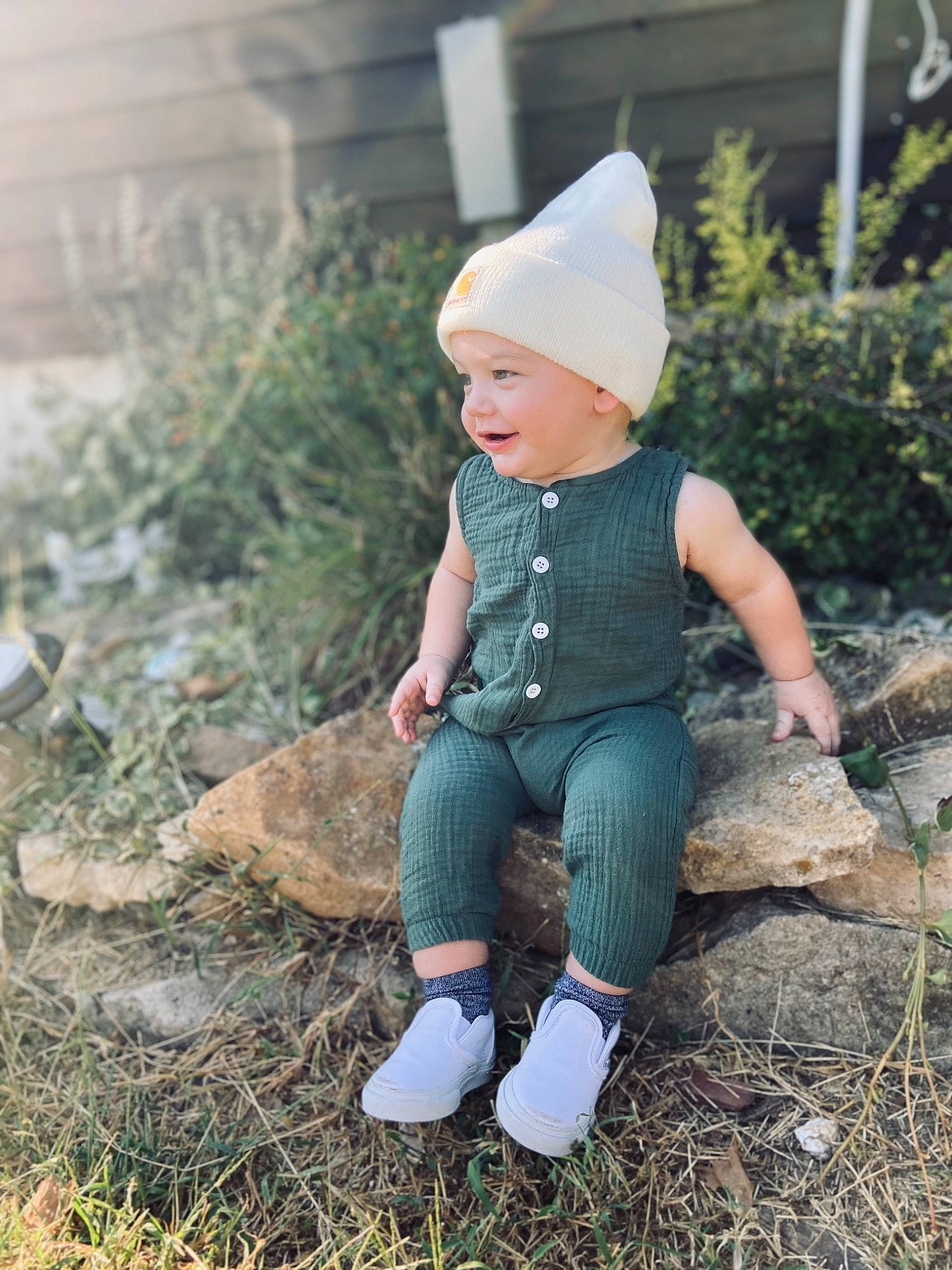 Zayden is registered to the contest to win money with this photo: baby, cap, child, dress, eye, grass, happy, hat, headwear, lawn_ornament, leaf, outerwear, pattern, people_in_nature, person, plant, sitting, toddler, tree, winter
