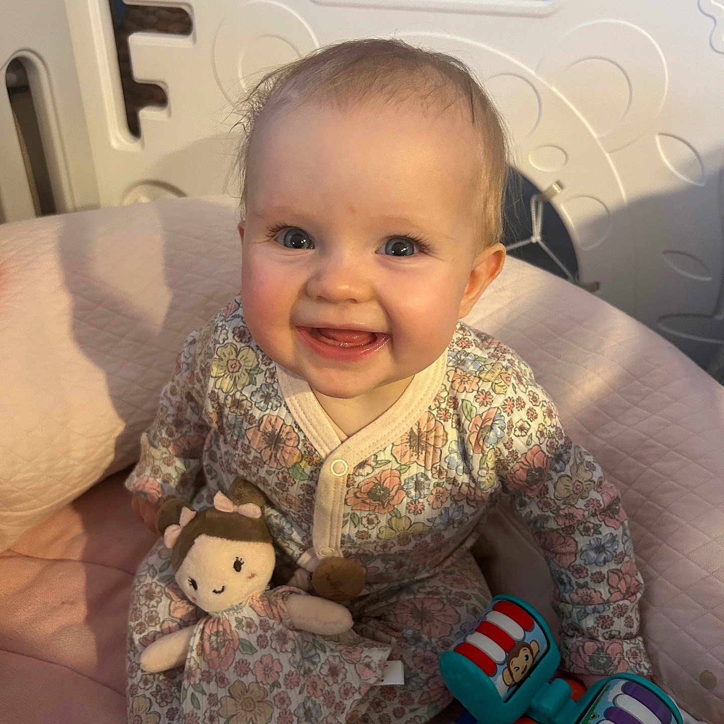 Eliya a rejoint le concours — aidez-le/la à gagner de superbes lots ! baby, child, smiling, blue_eyes, doll, toy, cushion, pink, floral_pattern, clothing, indoor, abacus, cute, happy, infant, playtime, portrait, person, sitting, soft_lighting