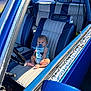 baby, pacifier, car, vintage_car, blue, leather_seat, steering_wheel, interior, child, sunlight, window, door, seat, infant, sitting, curious, automobile, classic_car, people, portrait