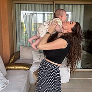Naël participe au concours pour gagner de l'argent avec cette photo : affection, baby, casual_clothing, curtain, floor, happy, holding, indoor, kiss, long_hair, love, pillow, polka_dot, skirt, smile, sofa, tattoo, watch, window, woman