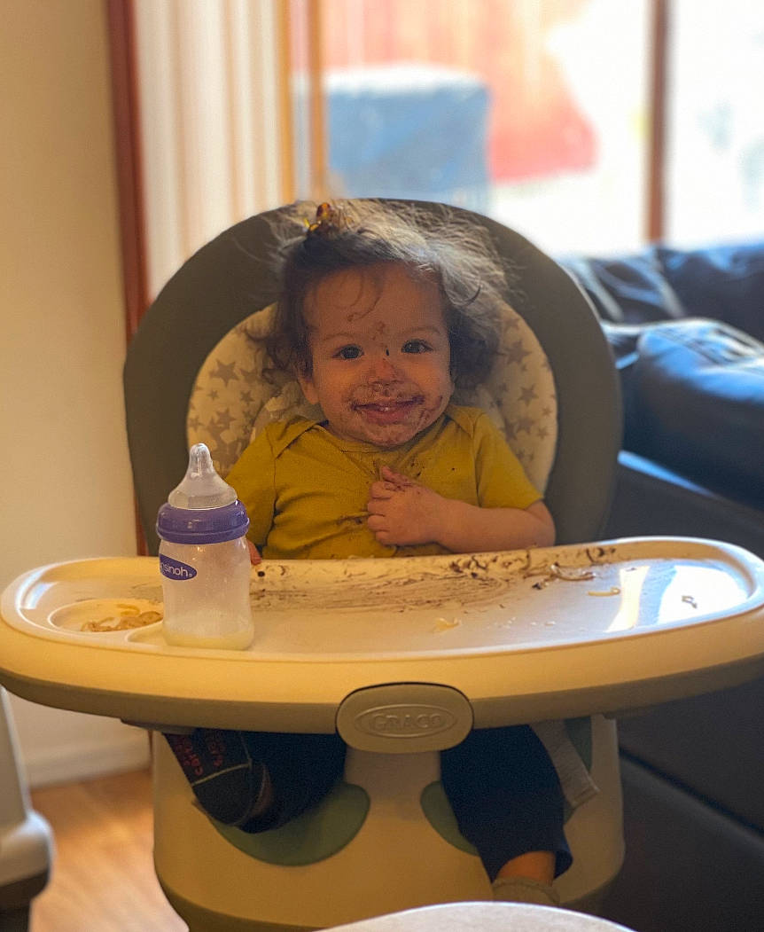 Adrien is registered to the contest to win money with this photo: baby, bottle, chair, child, comfort, event, fun, happy, joy, leisure, person, plastic_bottle, plate, room, sitting, skin, smile, table, tableware, toddler