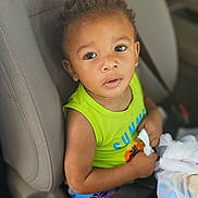 Kymere joined the competition — help win amazing prizes! child, toddler, car_seat, seat_belt, green_shirt, colorful_shorts, plastic_bag, curly_hair, indoor, car_interior, safety, seat, person, cute, young, baby, expression, holding, travel, looking_up