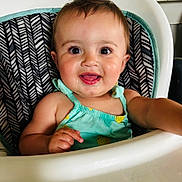 Ariella joined the competition — help win amazing prizes! baby, child, high_chair, smiling, happy, face, person, clothing, sitting, indoor, cute, portrait, young_child, infant, dressed, seat, furniture, skin, head, arm