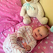 Valeria joined the competition — help win amazing prizes! baby, child, pajamas, bed, pink, hearts, teddy_bear, stuffed_animal, smiling, reaching_hand, cute, cozy, indoor, soft_toy, sleepwear, infant, happy, lying_down, bedroom, playful